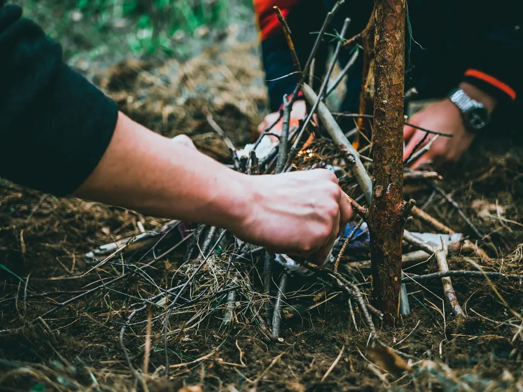 Persoon oefent met firestarter en hout in veilige buitenomgeving