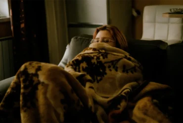 Persoon gewikkeld in een deken in een koude kamer zonder verwarming