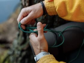 Handen die een knoop leggen in een groen paracord touw