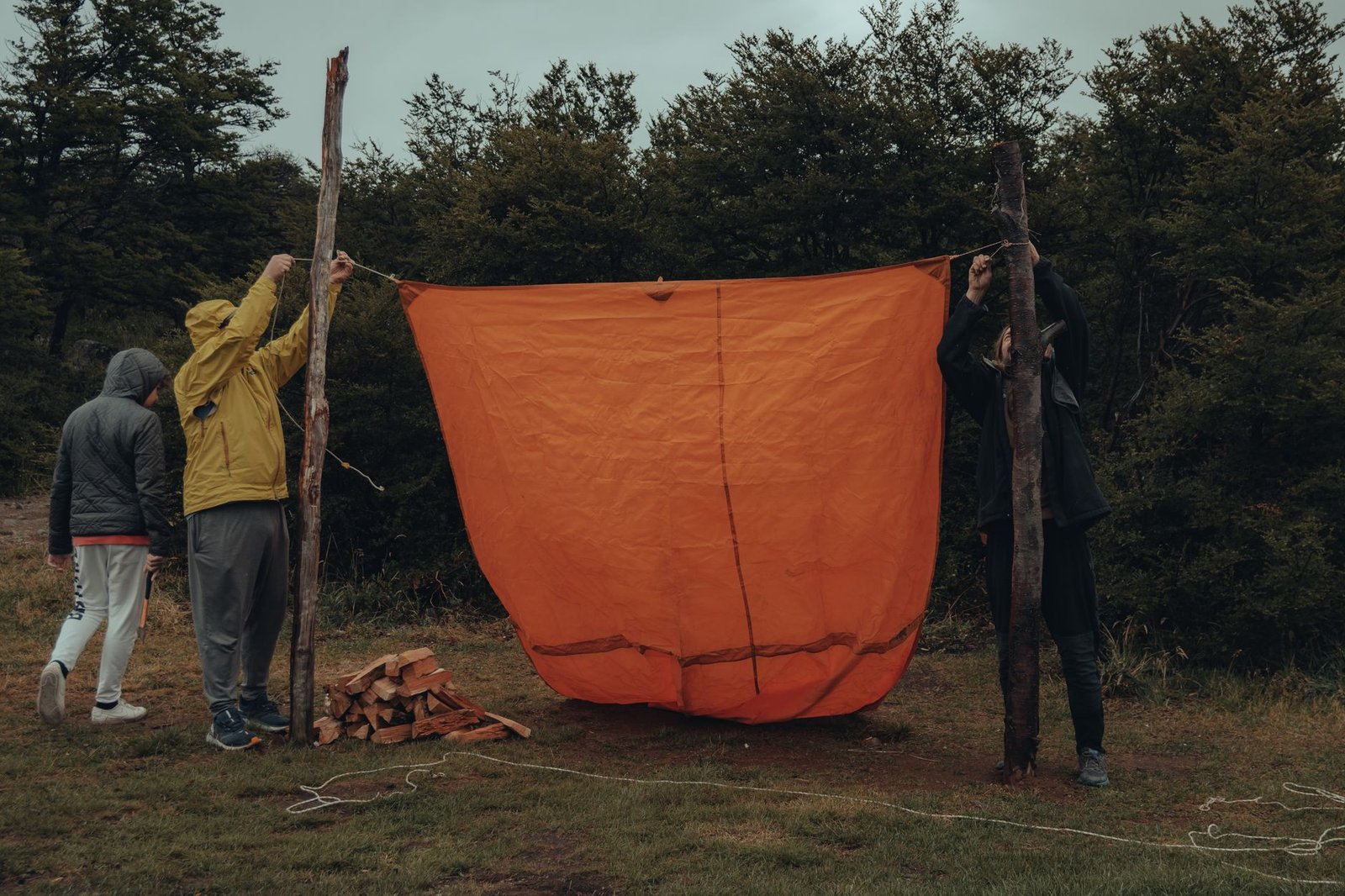 Mensen spannen een oranje tarp tussen twee palen met touw