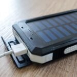 Powerbank met zonnepaneel en een aangesloten USB-kabel op een houten tafel