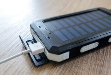 Powerbank met zonnepaneel en een aangesloten USB-kabel op een houten tafel