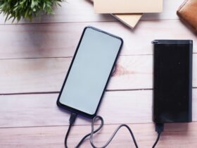 Smartphone wordt opgeladen met een zwarte powerbank op een houten tafel