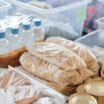 Voorraad flessen water, pasta en blikken voedsel in opbergbakken