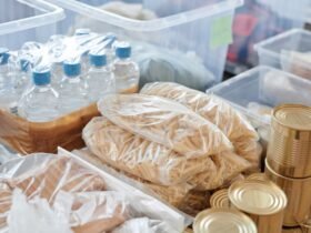 Voorraad flessen water, pasta en blikken voedsel in opbergbakken