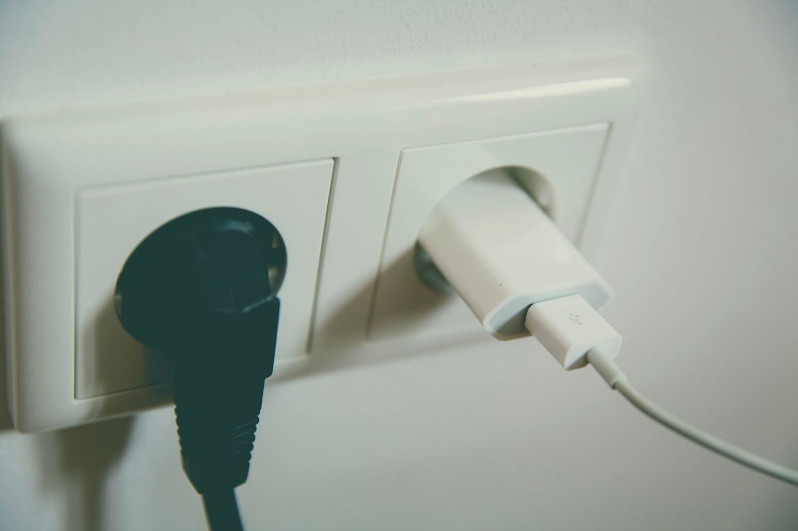 Twee stekkers in een stopcontact aan de muur