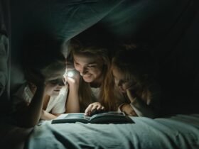 Moeder en kinderen onder een deken met een zaklamp tijdens een stroomstoring
