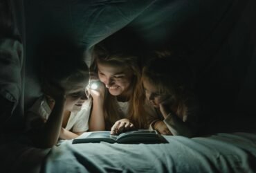 Moeder en kinderen onder een deken met een zaklamp tijdens een stroomstoring