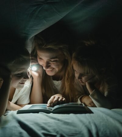 Moeder en kinderen onder een deken met een zaklamp tijdens een stroomstoring