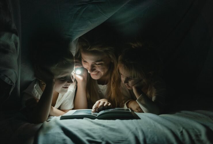 Moeder en kinderen onder een deken met een zaklamp tijdens een stroomstoring