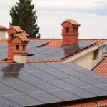 Daken met rode dakpannen en schoorstenen vol zonnepanelen
