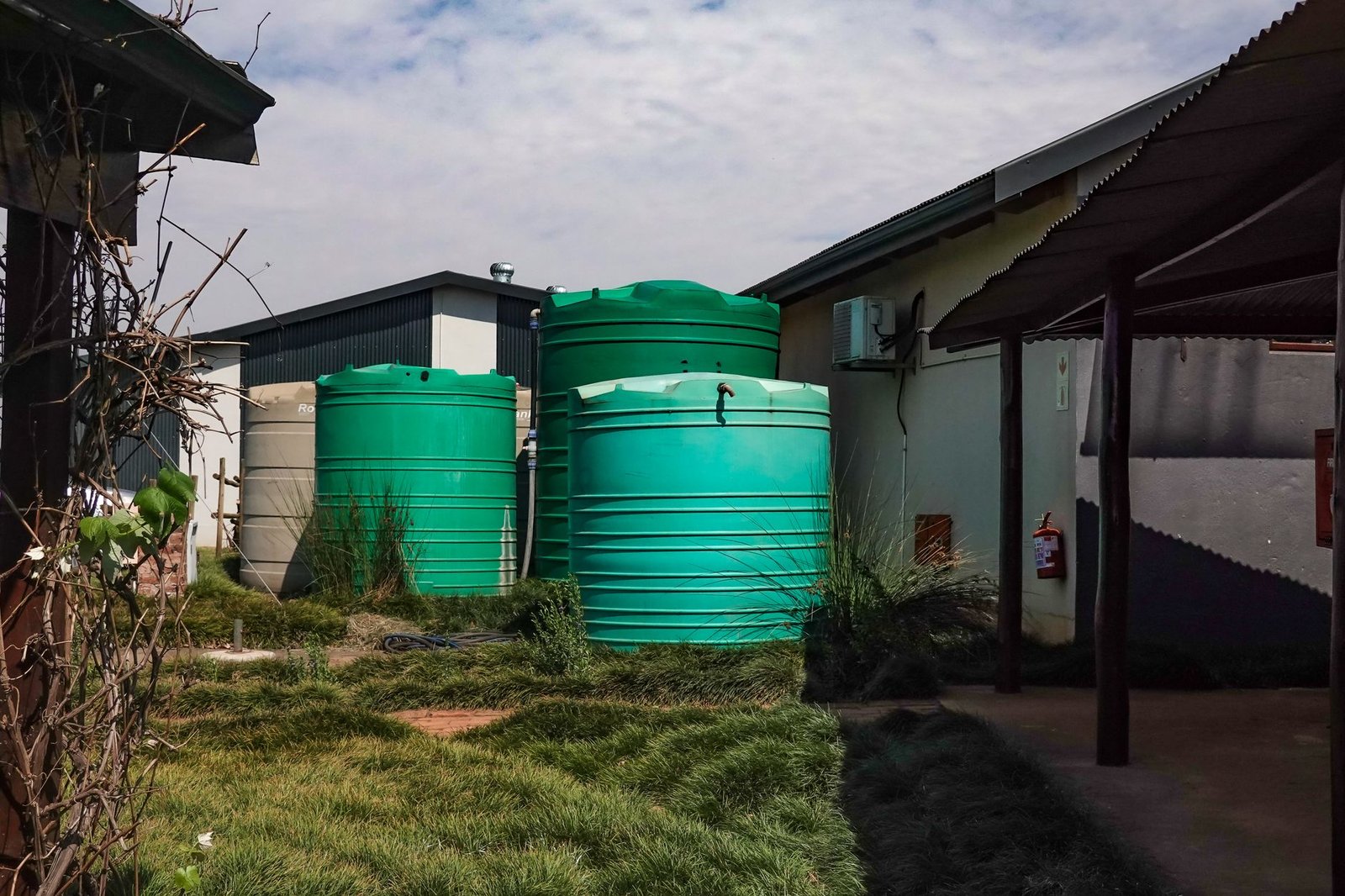 Drie grote groene watertanks naast een huis